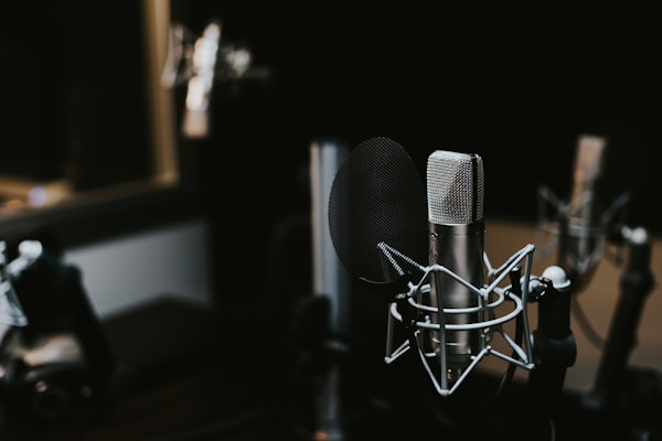 Personne âgée souriante portant des écouteurs devant un microphone de podcast